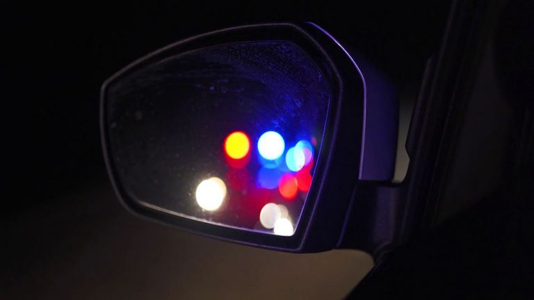 نور چراغ ماشین پلیس در آینه بغل خودرو در شب